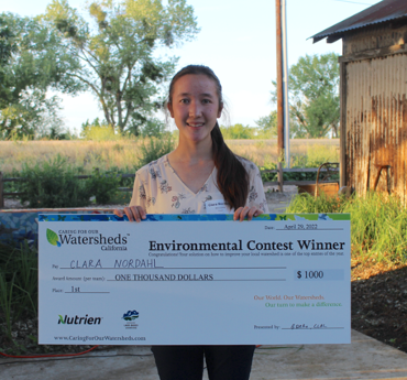 Student standing with $1000 Environmental Contest Winner cheque