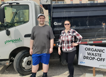 Man and woman posing in front of composting truck