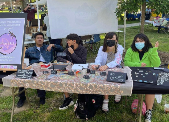 Students sitting behind promotion table for eco-friendly art