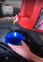 Oil being poured into a funnel into a vehicle