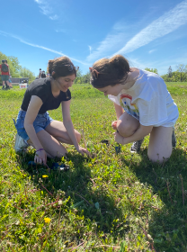 Two girls kneeling down looking at grass