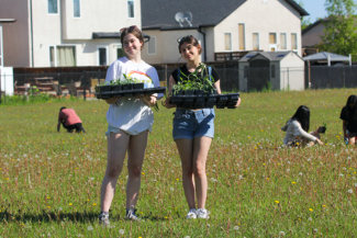 Two girls standing with plants growing in pots